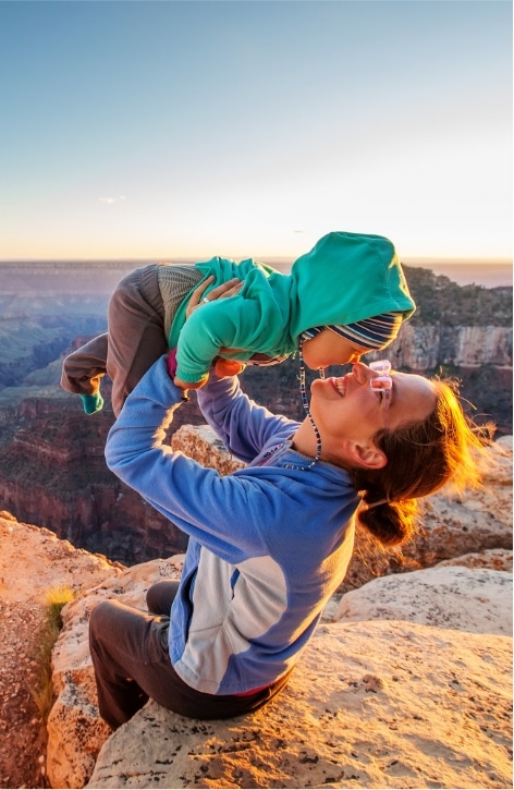 A mother lifting up her child while enjoying the sunset view from a rocky mountain in Handerson, NV